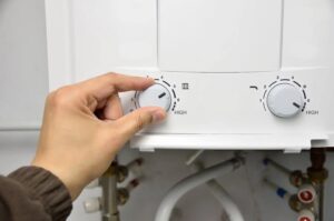 A homeowner adjusting the settings on a tankless water heater in their home